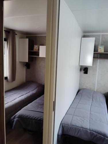 une petite chambre avec deux lits et un miroir dans l'établissement Mobil-home 