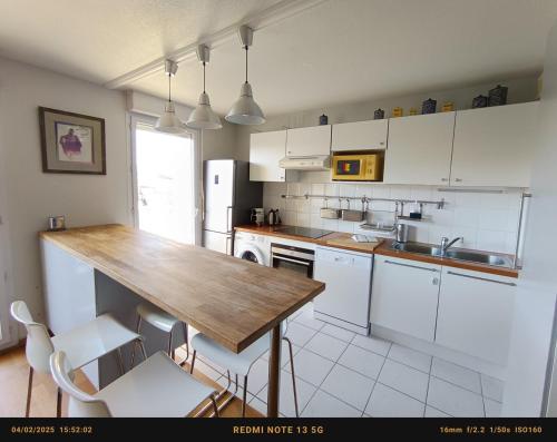 une cuisine avec une table en bois et des armoires blanches dans l'établissement Nice apartment central Bordeaux, à Bordeaux