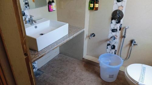 a bathroom with a sink and a trash can at Hotel Crown in Ahmedabad