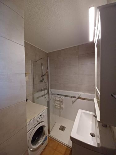une salle de bain avec une machine à laver et un lavabo dans l'établissement Sous le tilleul, à Gréoux-les-Bains