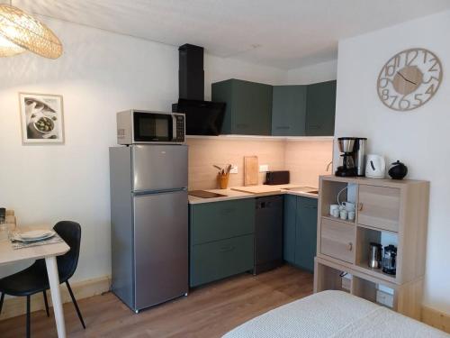 a small kitchen with green cabinets and a table at Sous le tilleul in Gréoux-les-Bains