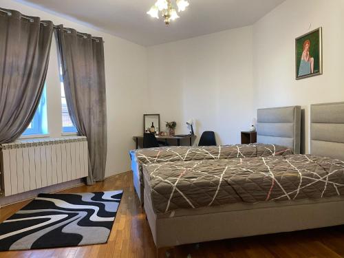 a bedroom with a bed and a desk and a window at Diplomat Haven in Sremska Kamenica