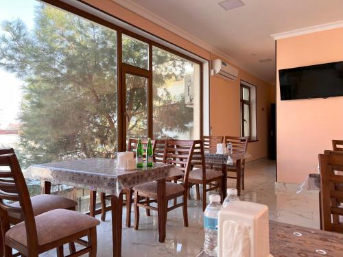 a dining room with tables and chairs and a large window at Silk Nest Hotel in Bukhara