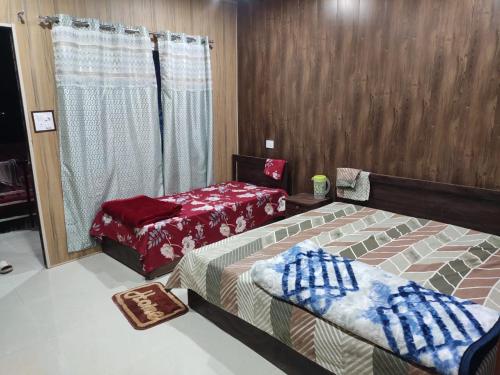a bedroom with two beds and a window at Hilans Hotel and Restaurant in Ukhimath