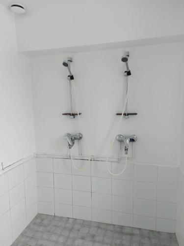 a shower in a bathroom with white tiles at Hostel Kulma in Lieksa