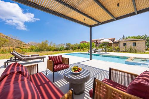 a patio with chairs and a table and a pool at Villa Lilia in Katelios
