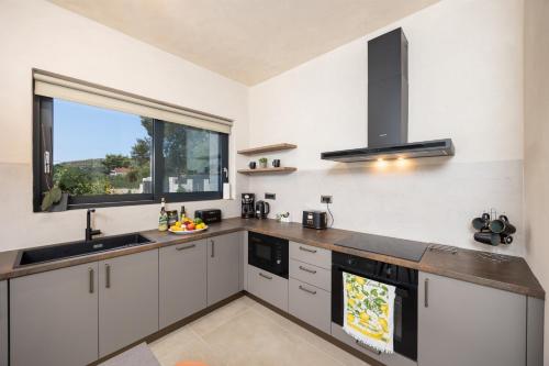 a kitchen with white cabinets and a large window at Villa Lilia in Katelios