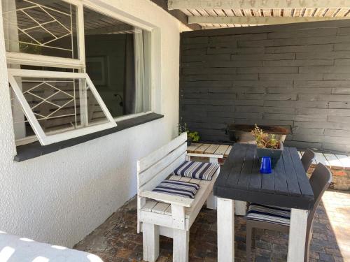 a table and chairs on a patio with a window at Willows Curve in Somerset West