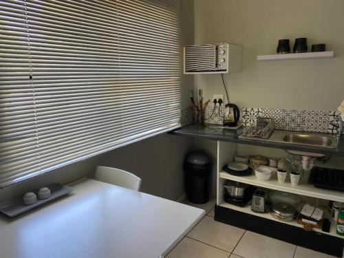a kitchen with a white table and a window at Willows Curve in Somerset West