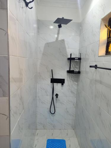 a white bathroom with a shower with a shower head at Camp William's - A dreamer's paradise in Kiambu in Kanyore