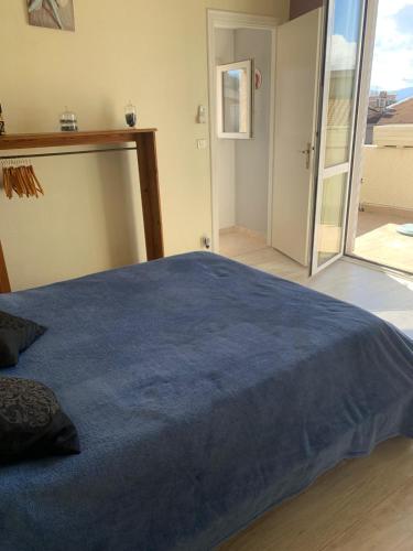 - une chambre avec un grand lit bleu et une porte coulissante en verre dans l'établissement Sables de biguglia cordon lagunaire, à Borgo