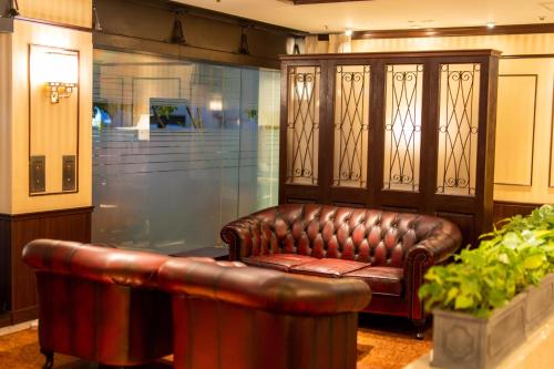 a brown leather couch sitting in a room with a plant at Ramada Encore by Wyndham Amagasaki in Amagasaki