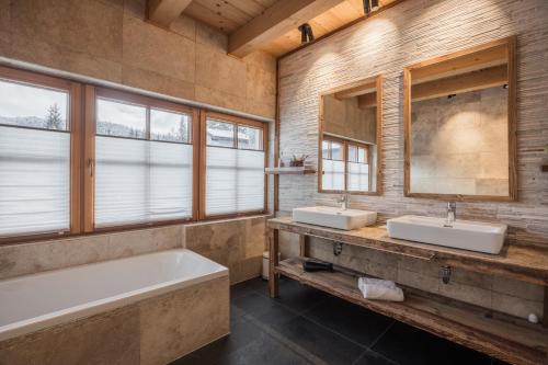 łazienka z 2 umywalkami, wanną i 2 lustrami w obiekcie IM WEIDACH Superior Chalets w mieście Leutasch
