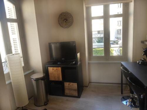 - un salon avec une télévision et 2 fenêtres dans l'établissement Charmant studio au cœur de Dijon, à Dijon
