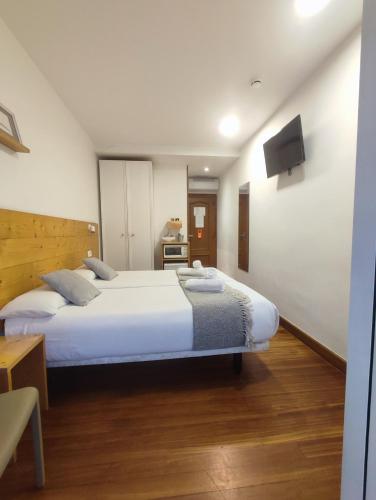 a bedroom with two beds and a tv on the wall at Pensión Urkia in Donostia-San Sebastián