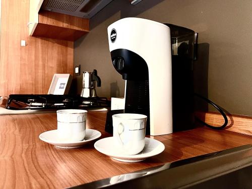 two coffee cups on a counter next to a coffee maker at Rosso Apartment in Alba