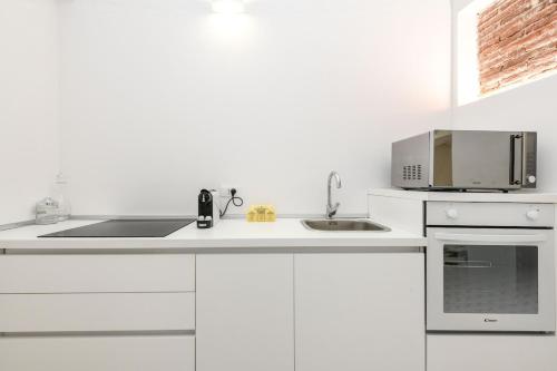a white kitchen with a microwave and a sink at White Loft -Bijou- tra Verona e il Lago di Garda in Pescantina