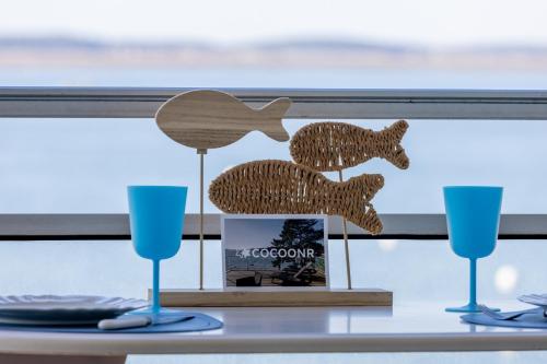 two wooden animals on a table with two blue glasses at Au bord de l'eau - Vue imprenable sur le bassin in Arcachon