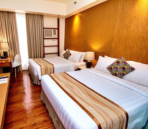 a hotel room with two beds and a desk at Ferra Premier by JG in Boracay