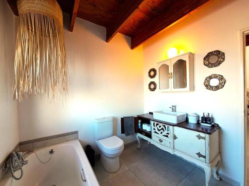a bathroom with a sink and a toilet and a tub at Saint Anna Beach House in St Helena Bay