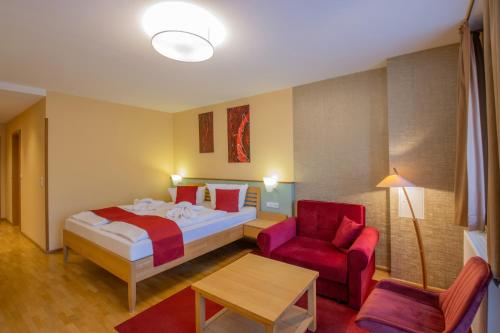 a hotel room with a bed and a red chair at Ferien Residenz Thüringer Wald in Masserberg