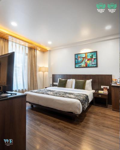 a hotel room with a bed and a television at Woodrock Luxury Boutique Hotel in Manāli