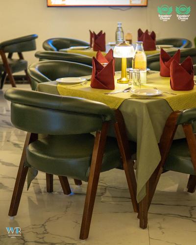 a table with green chairs and a yellow table cloth at Woodrock Luxury Boutique Hotel in Manāli