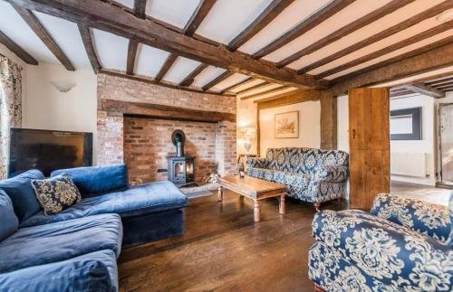 a living room with blue couches and a fireplace at Bramble Cottage in Atcham
