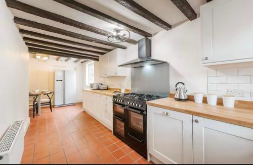 a kitchen with white cabinets and a stove top oven at Bramble Cottage in Atcham