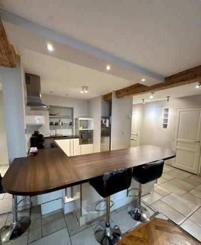 une grande cuisine avec une table en bois et deux tabourets de bar dans l'établissement Appartement moderne, Lyon 6ème, à Lyon