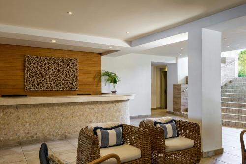 a lobby with two chairs and a bar at Waves Resort & Spa, Barbados, An Autograph Collection All-Inclusive Resort in Saint James