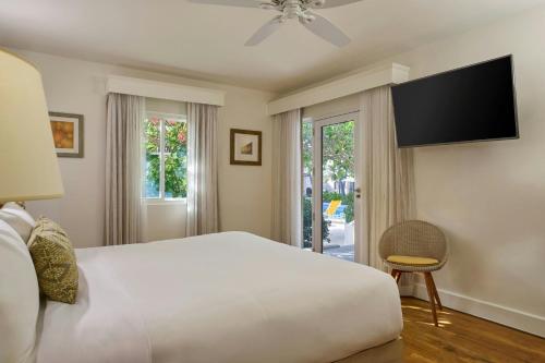 a bedroom with a large bed and a flat screen tv at Waves Resort & Spa, Barbados, An Autograph Collection All-Inclusive Resort in Saint James
