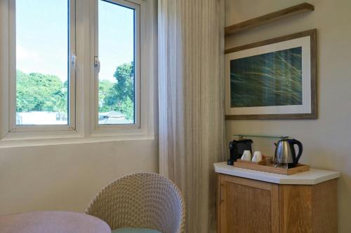 a room with two windows and a table and chairs at Waves Resort & Spa, Barbados, An Autograph Collection All-Inclusive Resort in Saint James