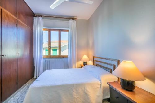 a bedroom with a bed with a lamp and a window at Italianway - Rossetti 3 in Marina di Cecina