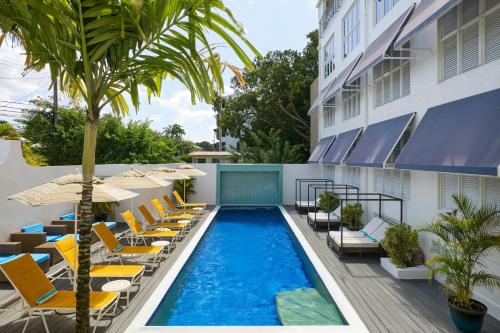 a swimming pool with lounge chairs and a hotel at Waves Resort & Spa, Barbados, An Autograph Collection All-Inclusive Resort in Saint James