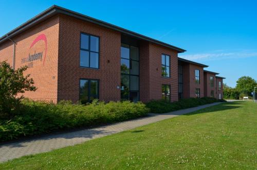a brick building with a grassy yard in front of it at Sport & Academy in Farsø