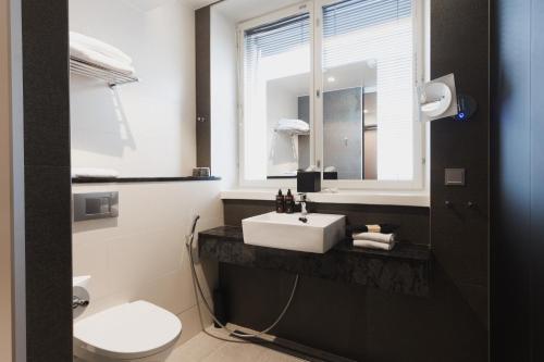 a bathroom with a sink and a toilet and a mirror at Home Hotel Jugend in Helsinki