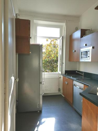 Il comprend une cuisine équipée d'un réfrigérateur en acier inoxydable et une fenêtre. dans l'établissement 117m2 - spacieux et lumineux, à Périgueux