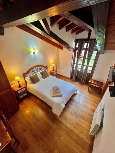 a bedroom with a large bed and wooden floors at Hotel Rural El Sestil in Dobres