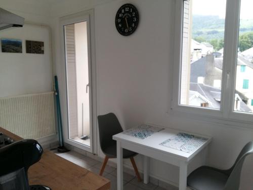 une pièce avec une table et une horloge au mur dans l'établissement Vue sur montagne, à Bagnères-de-Bigorre