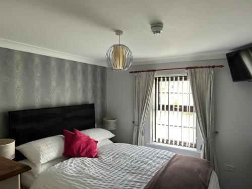 a bedroom with a bed with red pillows and a window at Flambards Hotel in Cardigan