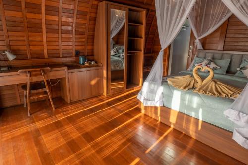 a bedroom with a bed with two swans on it at Lumbung River Ubud Villas in Blahbatu