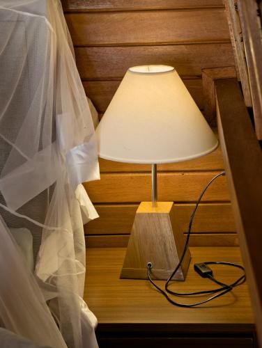 a lamp on a table with a wedding veil at Lumbung River Ubud Villas in Blahbatu