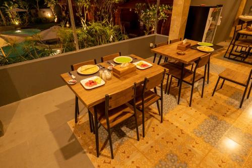 two wooden tables and chairs with plates of food on them at Lumbung River Ubud Villas in Blahbatu