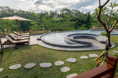 a swimming pool with a bench and an umbrella at Lumbung River Ubud Villas in Blahbatu