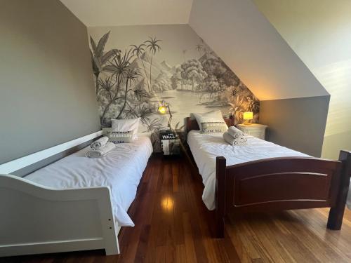 - 2 lits dans une chambre avec une fresque murale dans l'établissement Gîte les Bruyères, à Hesdin-lʼAbbé