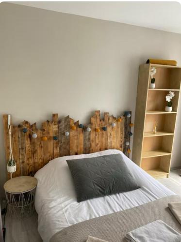 une chambre avec un lit avec une tête de lit en bois dans l'établissement Ma chambre côté Bassin, à Audenge