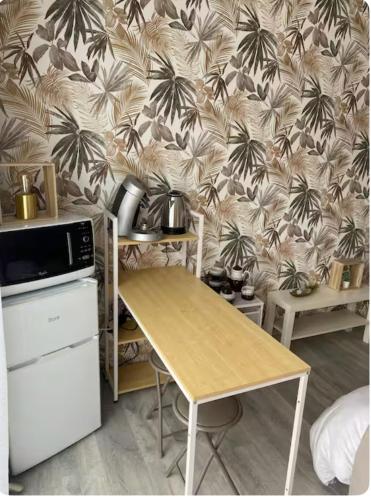 - une cuisine avec une table et du papier peint avec des palmiers dans l'établissement Ma chambre côté Bassin, à Audenge
