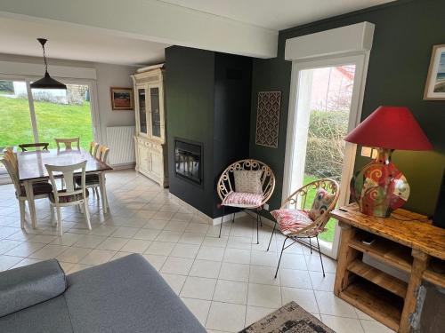 un salon avec une table et des chaises et une cheminée dans l'établissement Gîte les Bruyères, à Hesdin-lʼAbbé