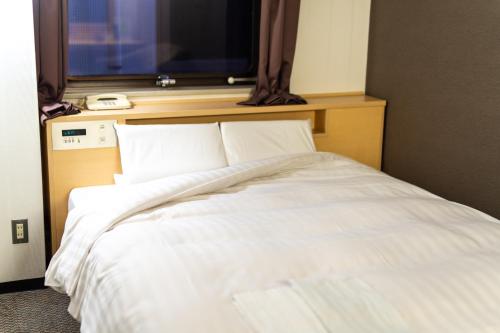 a white bed in a room with a window at Ramada Encore by Wyndham Amagasaki in Amagasaki